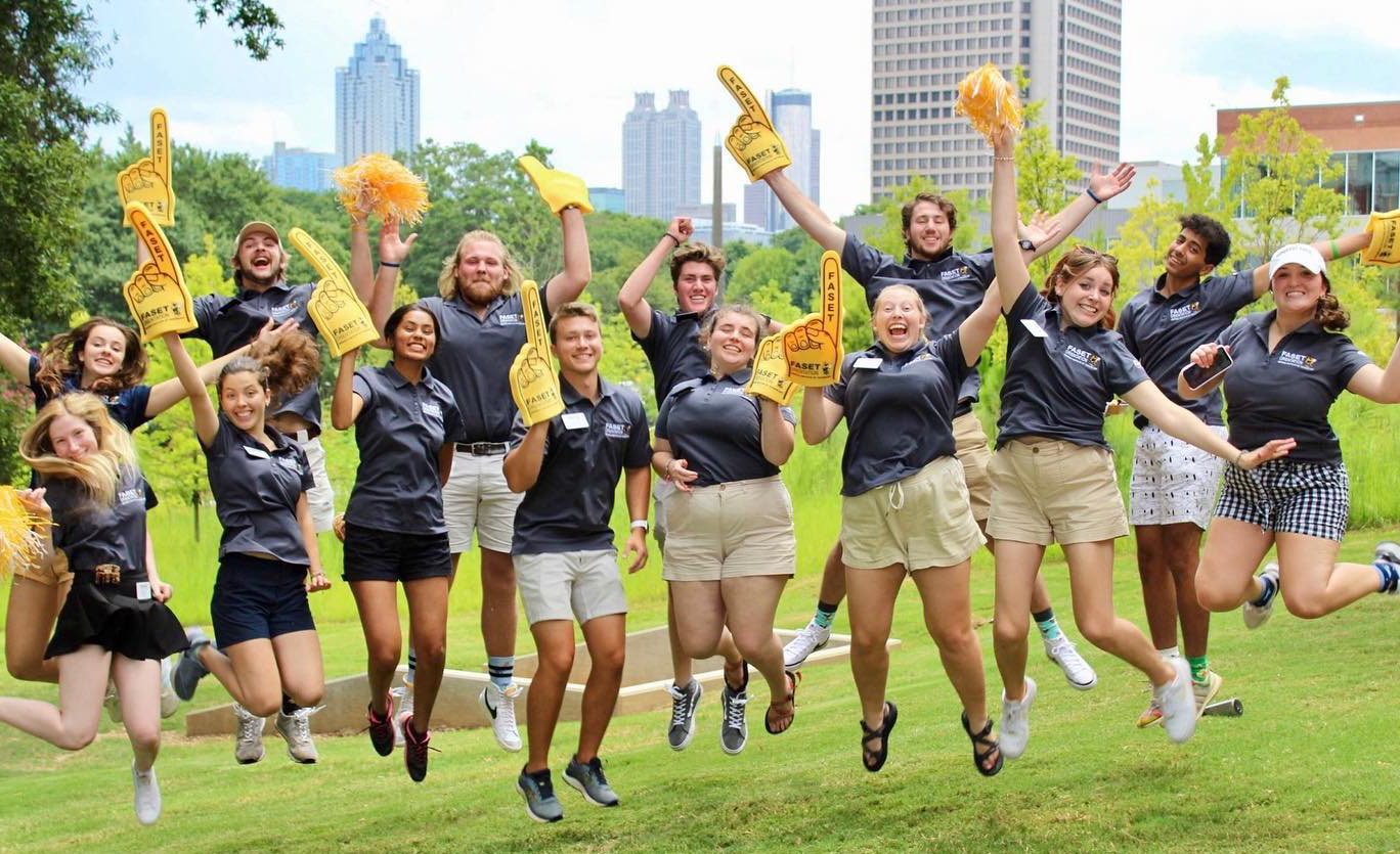 Group of happy 2022 FASET leaders jumping. Some holding pom poms and others foam fingers.