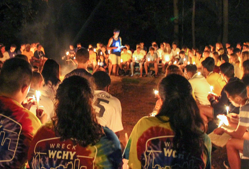 Wreck campers in a circle lighting candles.