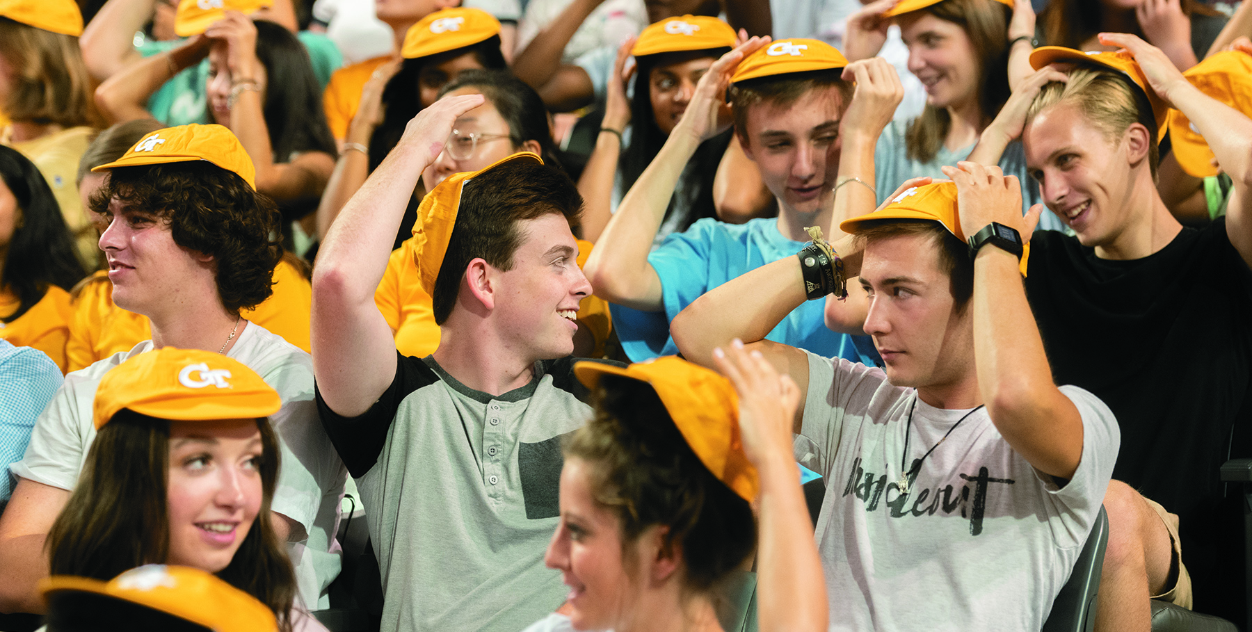 a group of college aged people all in various stages of putting on small yellow caps